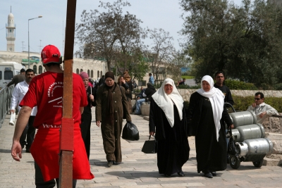 Counties evangelist Clive Cornish walks with his cross in Jerusalem while two Muslim ladies look with interest - during a project called From Jerusalem to Rome in the Footsteps of the Apostle Paul.