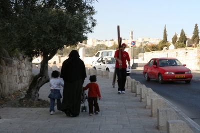 Counties evangelist Clive Cornish walks with his cross through Jerusalem close to the Mount of Olives. A Muslim family pass by during a project called From Jerusalem to Rome in the Footsteps of the Apostle Paul.