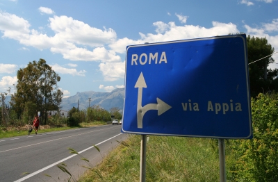 Counties evangelist Clive Cornish walks past a sign to Rome and the Via Appia with his cross – photographed during a project called From Jerusalem to Rome in the Footsteps of the Apostle Paul. Counties evangelist Clive Cornish walks past a sign to Rome and the Via Appia with his cross - photographed during a project called From Jerusalem to Rome in the Footsteps of the Apostle Paul.