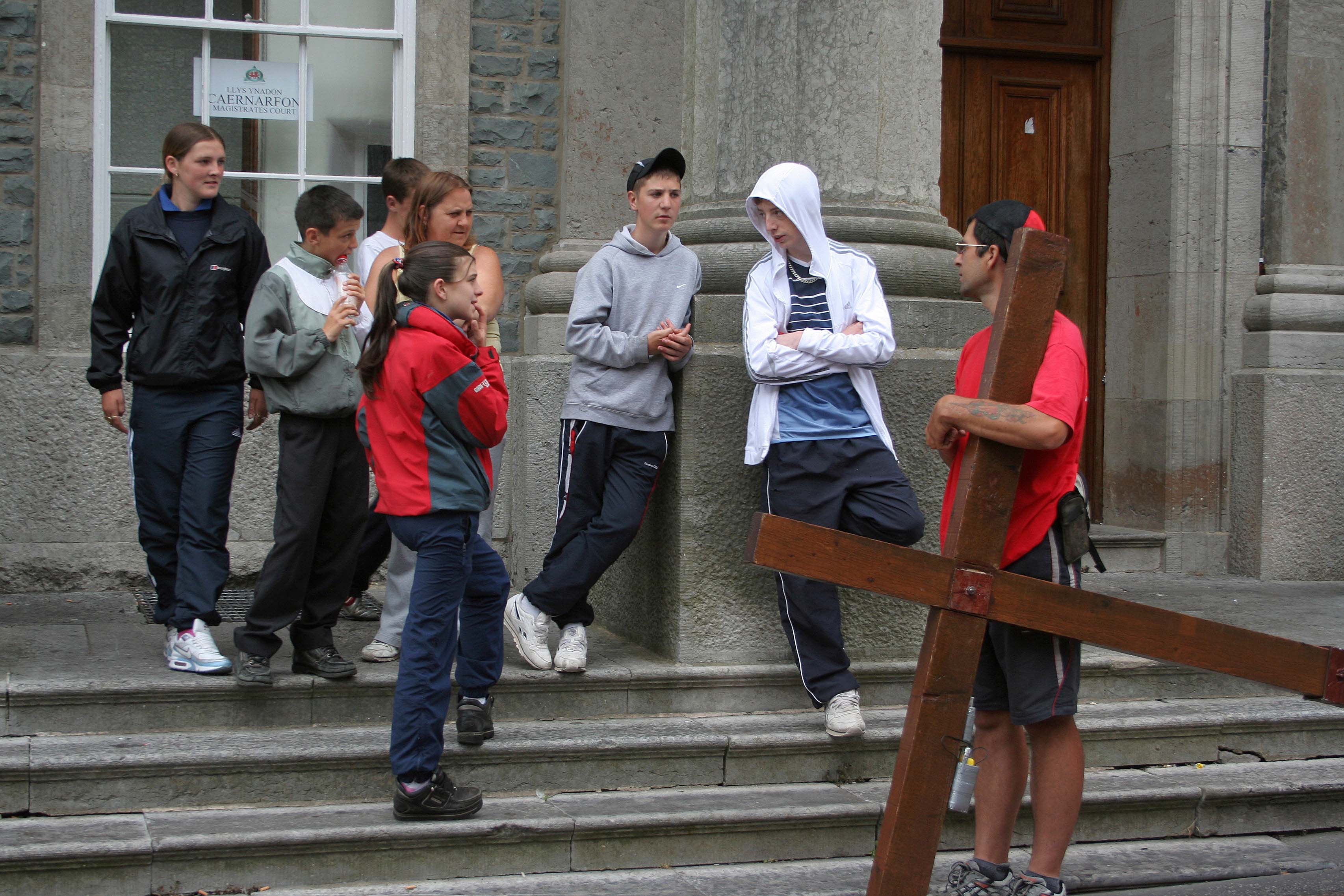 Counties evangelist Clive Cornish stops while carrying his cross to talk with a group of young people outside Caernarfon Magistrates Court