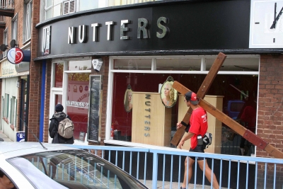 Counties evangelist Clive Coirnish walks with his cross past a hairdressers called Nutters in Exeter, Devon
