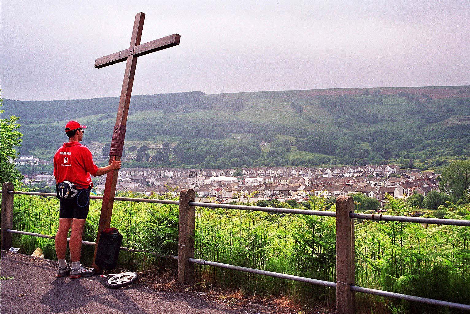 Counties evangelist Clive Cornish raises his cross above the Valleys of South Wales and prays for the villagers. A guided pilgrim walk in wales